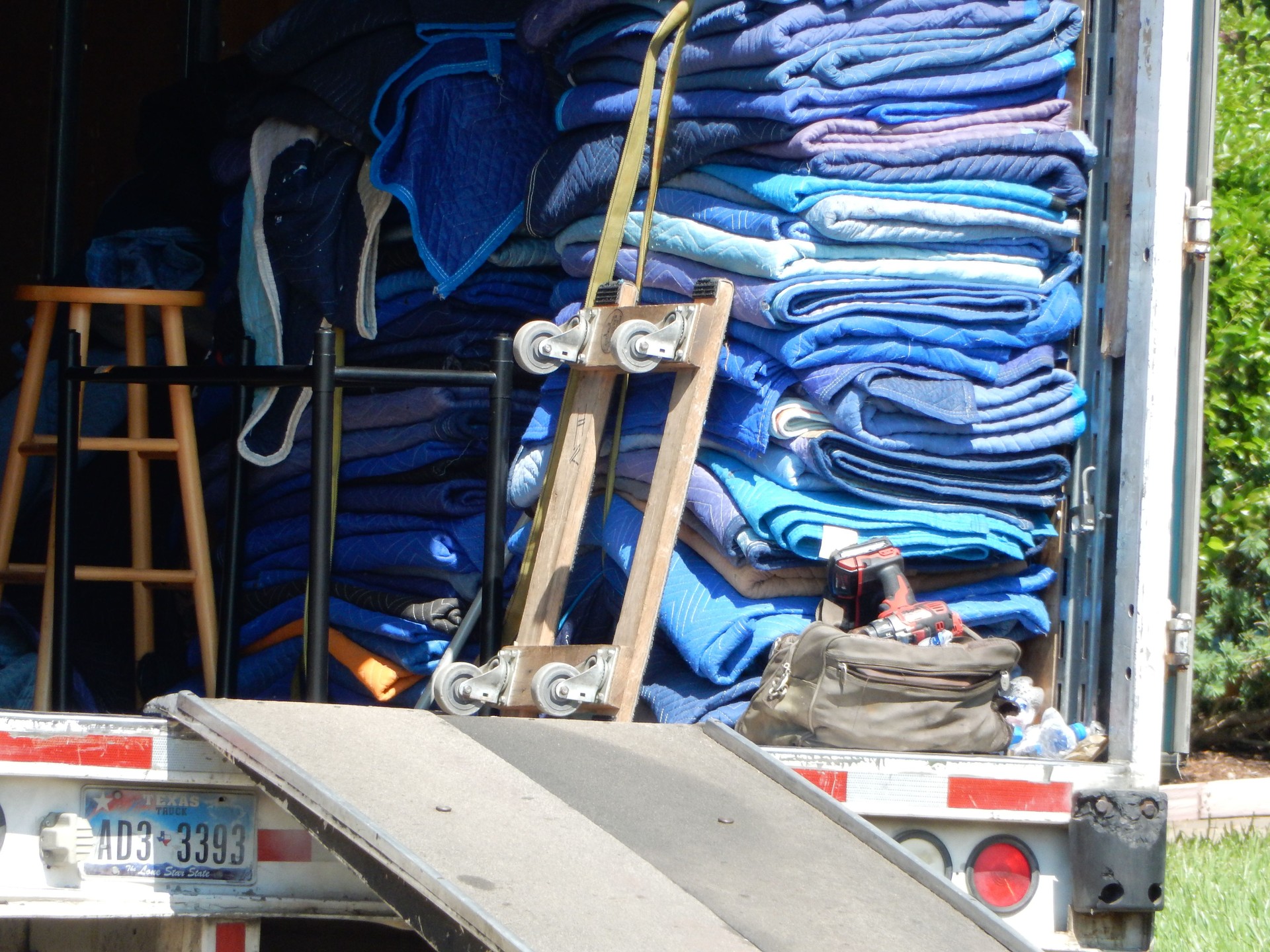 Back of moving truck open with blue moving blankets in back